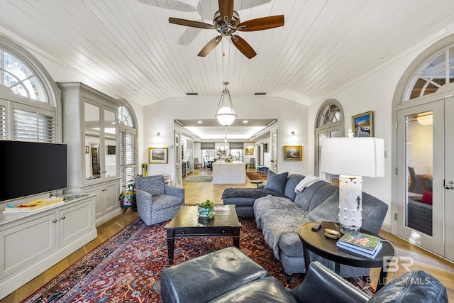 living room featuring lofted ceiling, french doors, light wood-type flooring, and crown molding