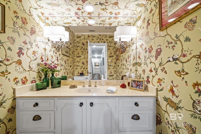 bathroom with wallpapered walls, ornamental molding, and vanity