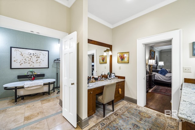 bathroom with baseboards, ensuite bath, vanity, a freestanding bath, and crown molding