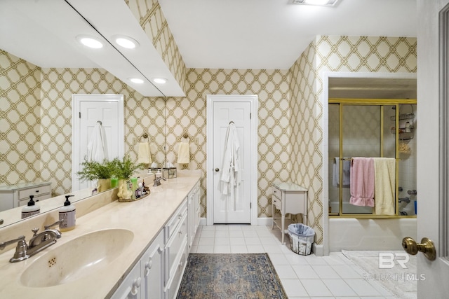 bathroom featuring bath / shower combo with glass door, tile patterned flooring, a sink, and wallpapered walls