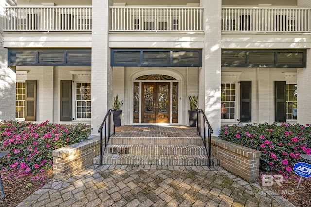 property entrance with brick siding, covered porch, and french doors