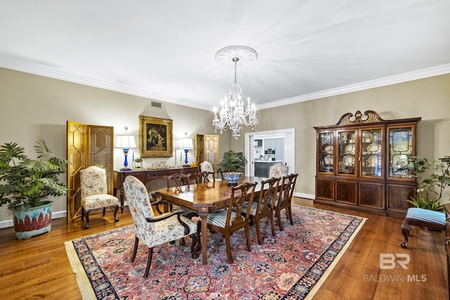 dining area featuring baseboards, a notable chandelier, ornamental molding, and wood finished floors