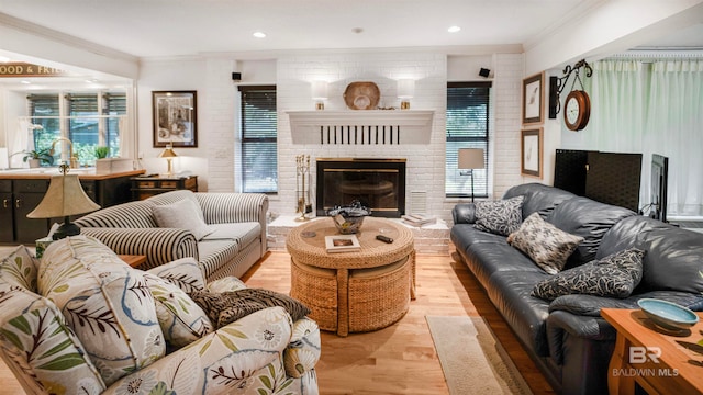 living room featuring brick wall, a fireplace, light wood-type flooring, and crown molding