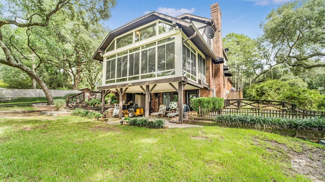 rear view of property featuring a yard and a sunroom