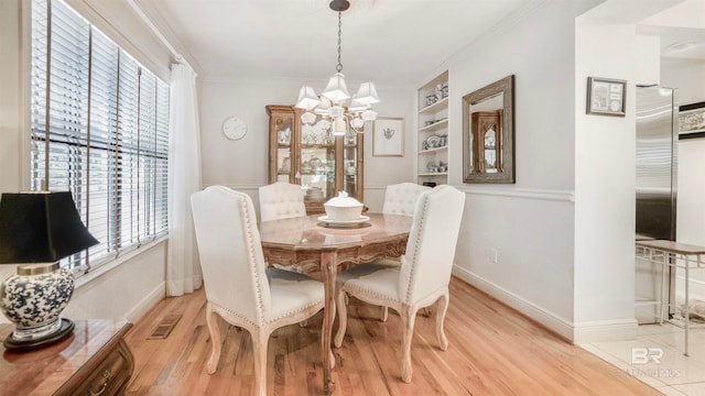 dining room featuring a healthy amount of sunlight, ornamental molding, a notable chandelier, and light hardwood / wood-style floors