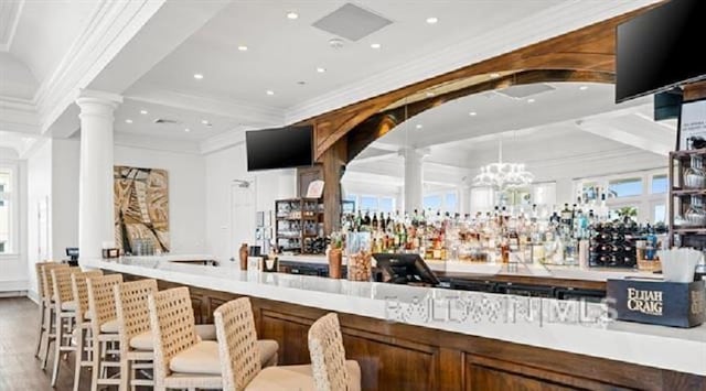 bar featuring light wood-type flooring, ornate columns, and crown molding