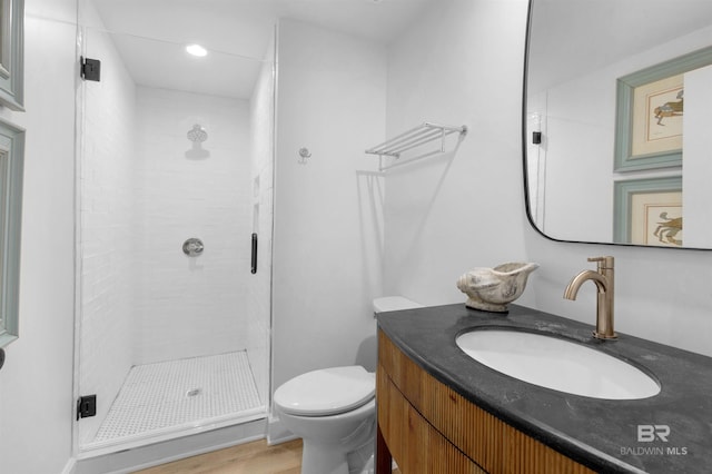 bathroom with a shower with shower door, vanity, and toilet