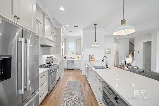 313 Cuban Lily Dr, Fairhope, AL 36532 - kitchen featuring premium appliances, a sink, light wood-style flooring, hanging light fixtures, and tasteful backsplash