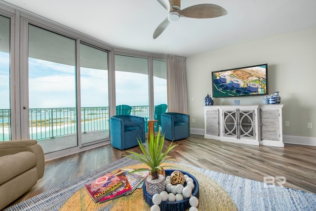 living room with a water view, a wall of windows, wood-type flooring, and ceiling fan