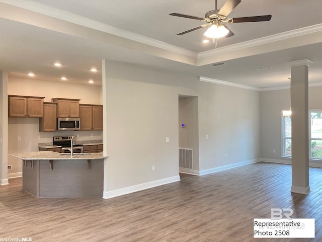 kitchen featuring appliances with stainless steel finishes, crown molding, a breakfast bar, and light stone counters