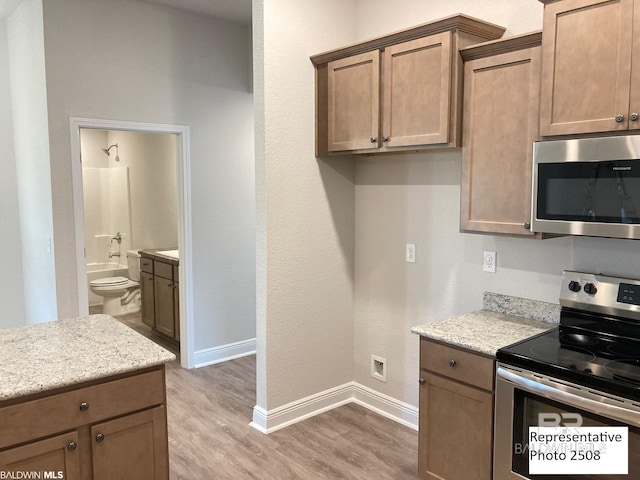 kitchen with hardwood / wood-style flooring, stainless steel appliances, and light stone counters