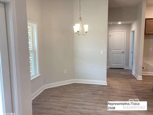 spare room with dark wood-type flooring and a notable chandelier