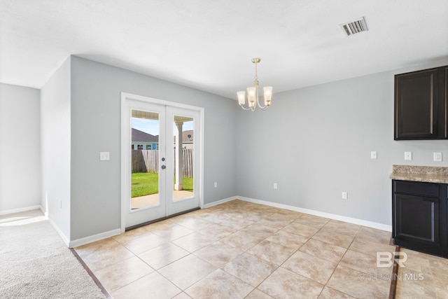 unfurnished dining area with french doors, an inviting chandelier, and light tile patterned flooring