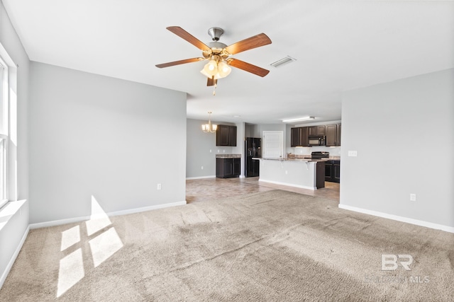 unfurnished living room with light carpet and ceiling fan with notable chandelier