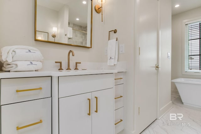 bathroom with vanity, a freestanding tub, recessed lighting, and marble finish floor