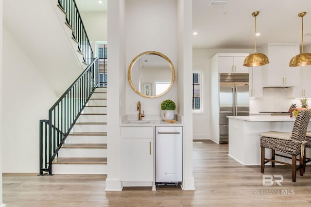 interior space featuring white cabinetry, light wood-style floors, built in fridge, and a sink