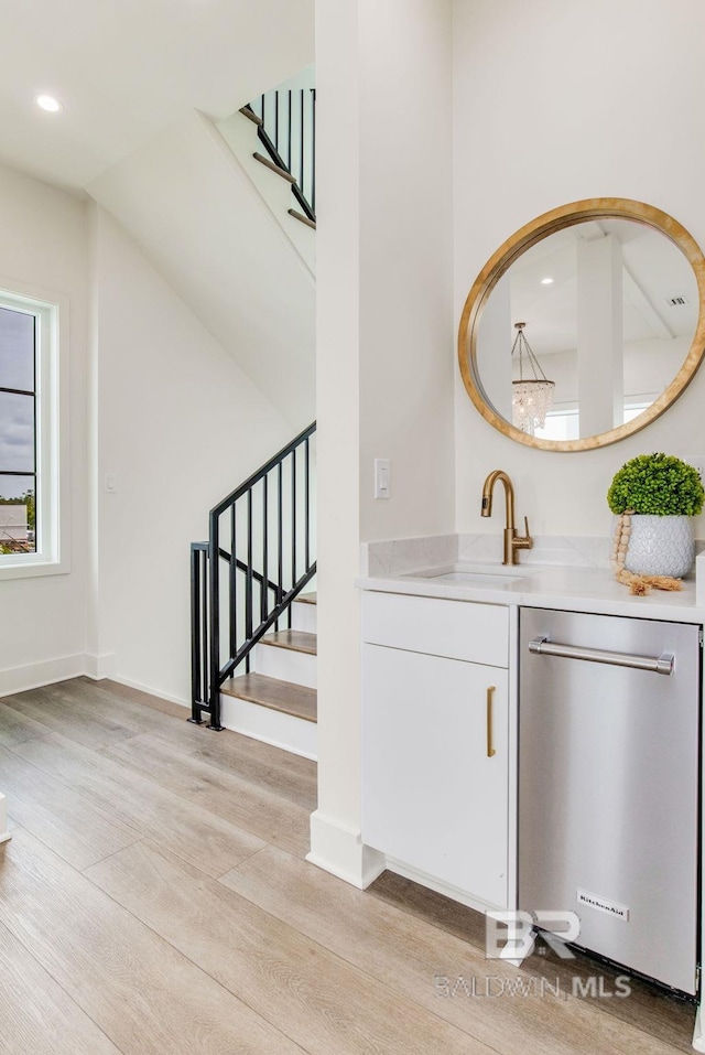 bar featuring recessed lighting, a sink, stairs, light wood-style floors, and dishwasher