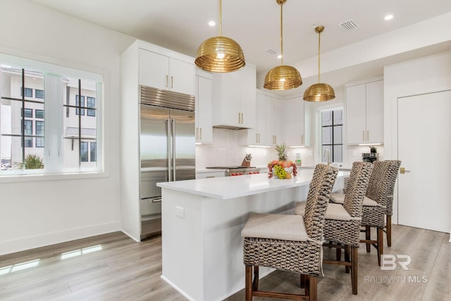 kitchen with visible vents, light wood-style flooring, built in refrigerator, and light countertops