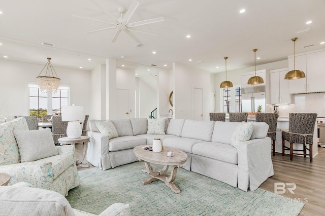 living room featuring recessed lighting, light wood-type flooring, a notable chandelier, and visible vents