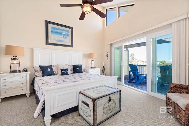 carpeted bedroom with multiple windows, access to exterior, a towering ceiling, and ceiling fan