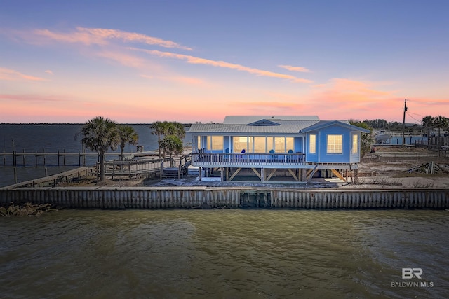 back of house with a water view and metal roof