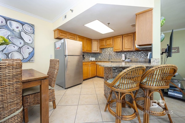 24230 Perdido Beach Blvd Unit 3112, Orange Beach, AL 36561 - kitchen with visible vents, backsplash, freestanding refrigerator, light tile patterned flooring, and crown molding