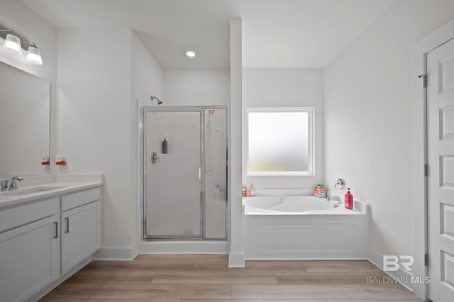 full bath featuring wood finished floors, vanity, a garden tub, and a stall shower