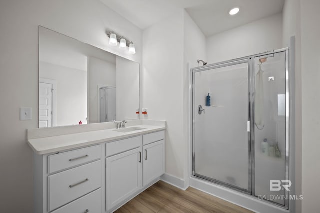 full bath with baseboards, a stall shower, wood finished floors, and vanity