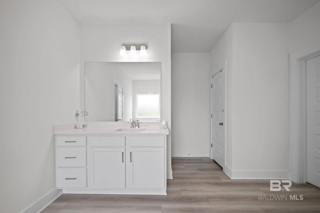 bathroom featuring vanity, wood finished floors, and baseboards