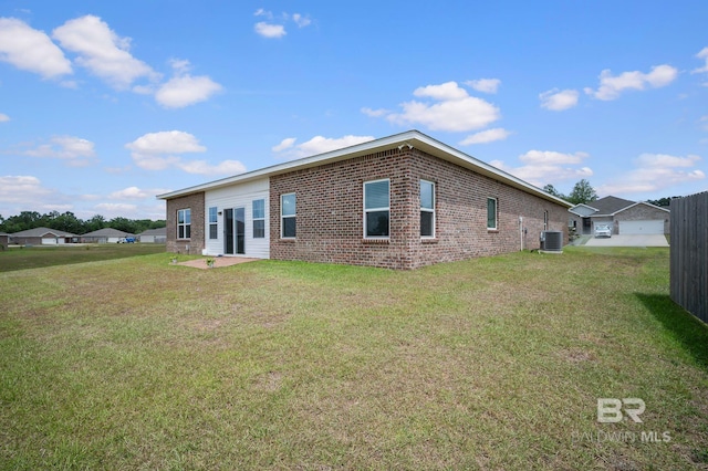 back of house with a yard, central air condition unit, a patio, and brick siding