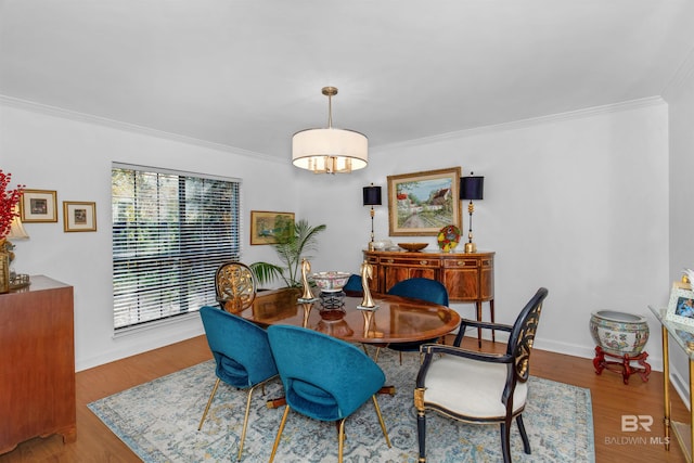 dining space featuring crown molding, baseboards, and wood finished floors