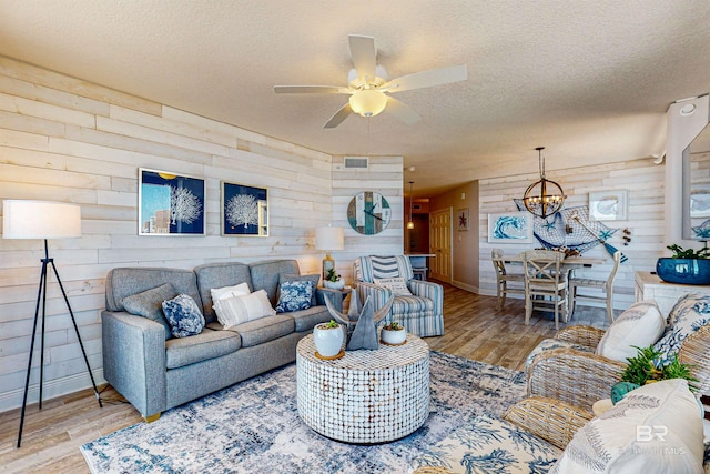 25020 Perdido Beach Blvd Unit 1101B, Orange Beach, AL 36561 - living room with wood walls, a chandelier, a textured ceiling, baseboards, and wood finished floors