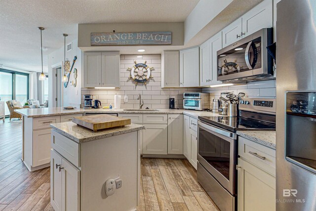 25020 Perdido Beach Blvd Unit 1101B, Orange Beach, AL 36561 - kitchen with appliances with stainless steel finishes, a sink, decorative backsplash, light wood-style floors, and a textured ceiling