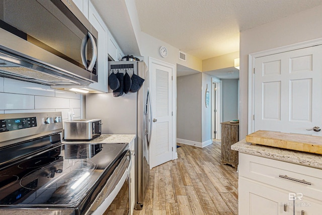 25020 Perdido Beach Blvd Unit 1101B, Orange Beach, AL 36561 - kitchen with stainless steel appliances, light wood-style floors, baseboards, white cabinets, and light stone countertops