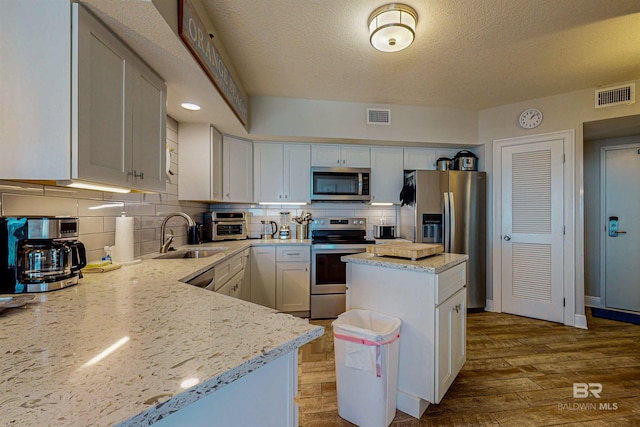 25020 Perdido Beach Blvd Unit 1101B, Orange Beach, AL 36561 - kitchen with stainless steel appliances, a sink, light stone countertops, backsplash, and a textured ceiling