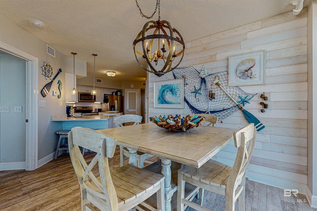 25020 Perdido Beach Blvd Unit 1101B, Orange Beach, AL 36561 - dining space with a chandelier, baseboards, a textured ceiling, and light wood-style flooring