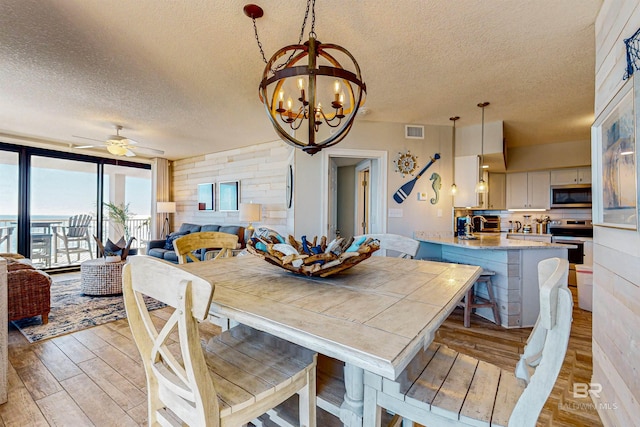 25020 Perdido Beach Blvd Unit 1101B, Orange Beach, AL 36561 - dining area featuring a textured ceiling, light wood-type flooring, ceiling fan, and a chandelier