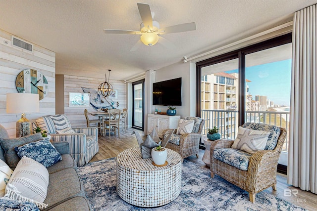 25020 Perdido Beach Blvd Unit 1101B, Orange Beach, AL 36561 - living area with light wood finished floors, a textured ceiling, plenty of natural light, a ceiling fan, and wood walls