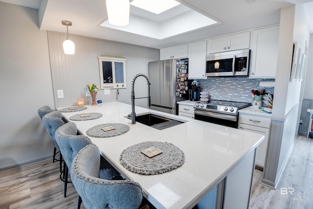 112 W 8th Ave Unit 7, Gulf Shores, AL 36542 - kitchen featuring appliances with stainless steel finishes, a sink, light wood finished floors, and white cabinetry