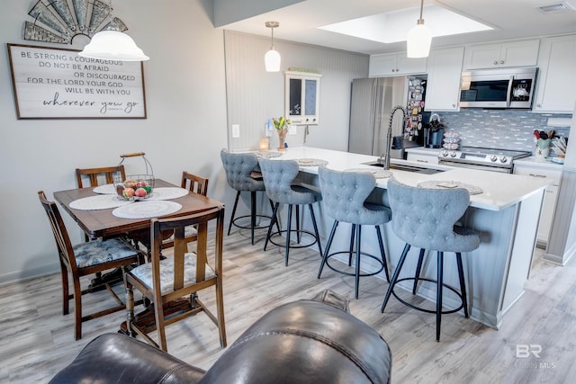 112 W 8th Ave Unit 7, Gulf Shores, AL 36542 - kitchen featuring stainless steel appliances, tasteful backsplash, a kitchen bar, and light wood-style flooring