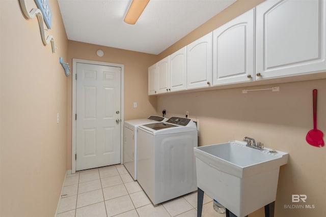 washroom with washer and clothes dryer, light tile patterned floors, cabinets, and sink