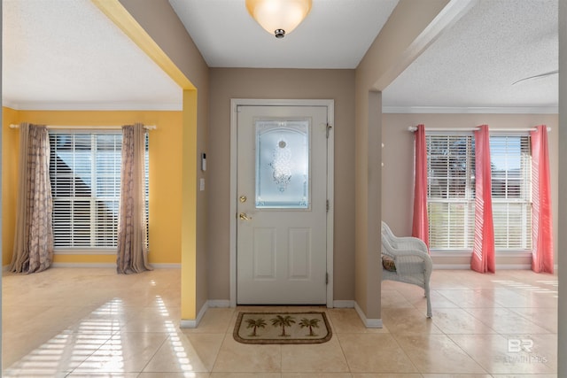 foyer entrance featuring a textured ceiling, light tile patterned floors, and crown molding