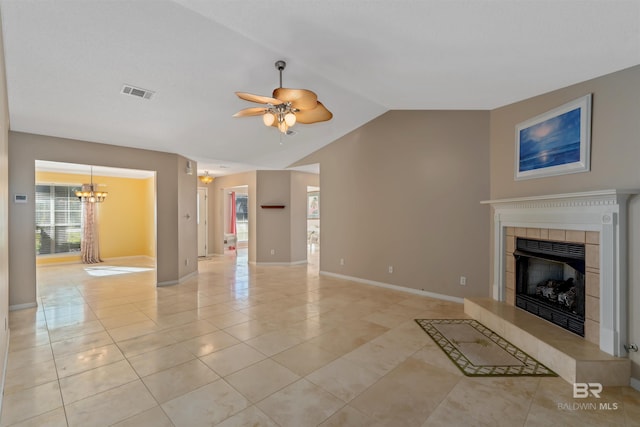 unfurnished living room with ceiling fan with notable chandelier, a tiled fireplace, light tile patterned floors, and vaulted ceiling