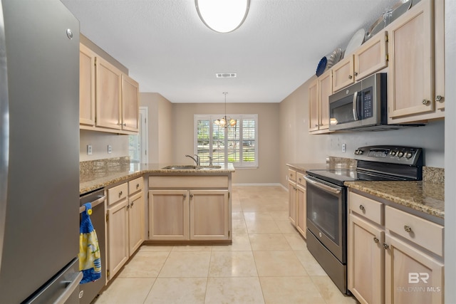 kitchen featuring light brown cabinets, hanging light fixtures, kitchen peninsula, light tile patterned floors, and appliances with stainless steel finishes