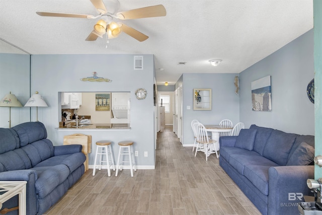 952 W Beach Blvd Unit 210, Gulf Shores, AL 36542 - living room featuring light wood-style flooring, baseboards, ceiling fan, and a textured ceiling