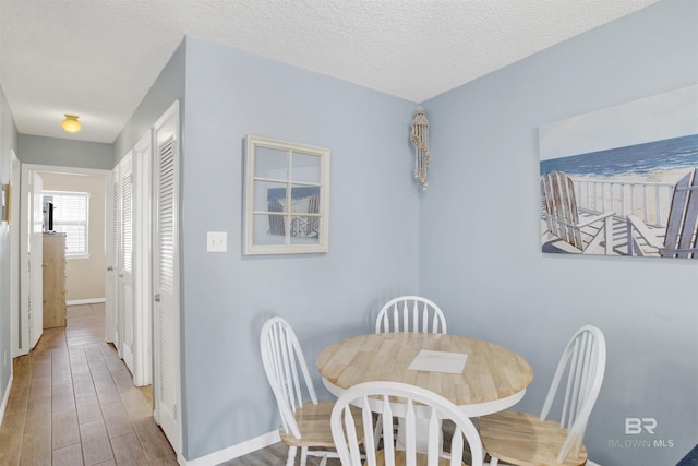 952 W Beach Blvd Unit 210, Gulf Shores, AL 36542 - dining area featuring wood finished floors, baseboards, and a textured ceiling