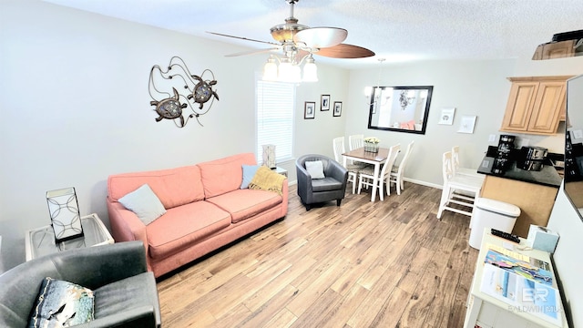 living room featuring ceiling fan, a textured ceiling, and light hardwood / wood-style floors