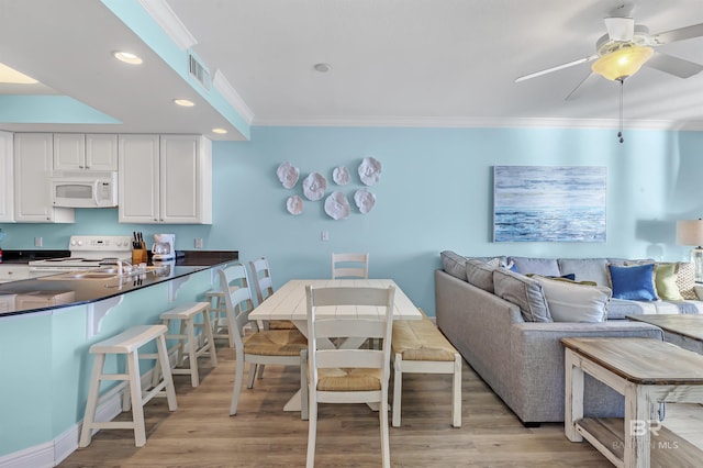 interior space with white appliances, visible vents, white cabinetry, ornamental molding, and dark countertops