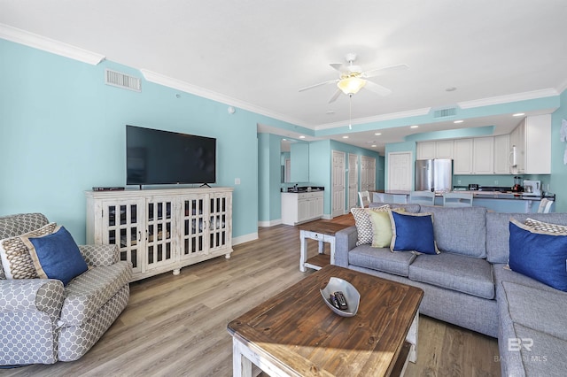 living area with light wood-style flooring, visible vents, and crown molding