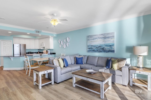 living area featuring baseboards, light wood-style flooring, ornamental molding, and a ceiling fan